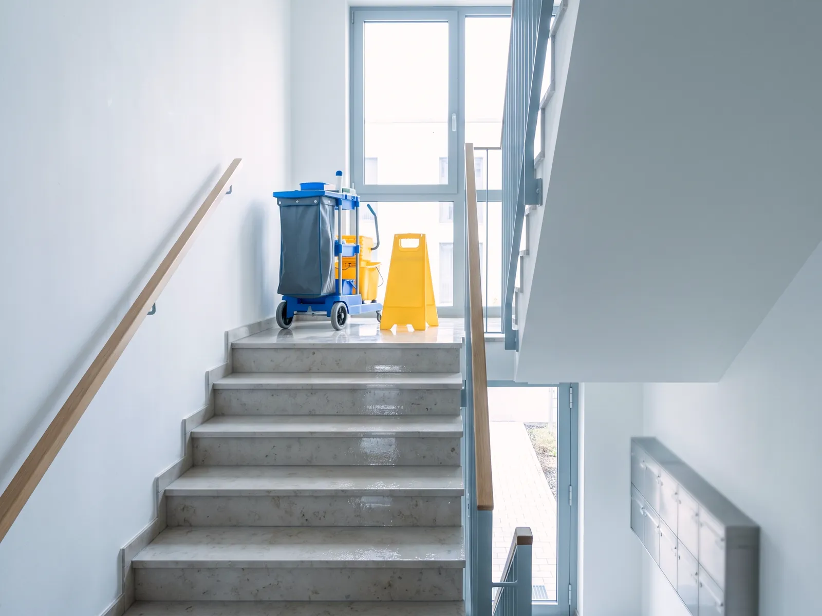 Frisch gereinigtes Treppenhaus mit Reinigungswagen in einem Mehrfamilienhaus
