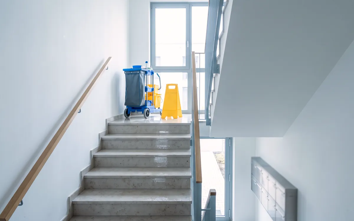 Frisch gereinigtes Treppenhaus mit Reinigungswagen in einem Mehrfamilienhaus